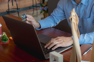 Midsection of woman using mobile phone while sitting on table