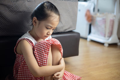 Rear view of a girl sitting on floor at home