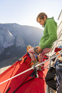 Athlete putting knee pad standing on portaledge on el capitan yosemite