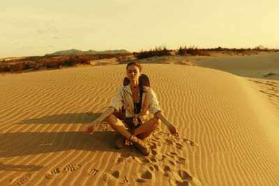 Full length of woman standing on sand at beach against sky during sunset