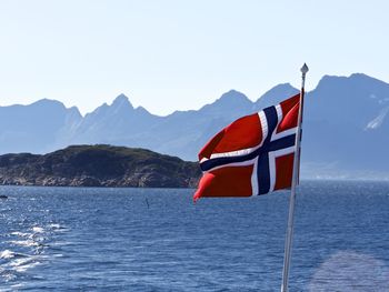 Norwegian flag in lake against mountain ranges