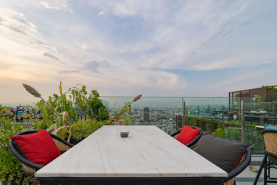 Chairs and table by swimming pool against sky