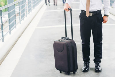 Low section of businessman standing with luggage at airport