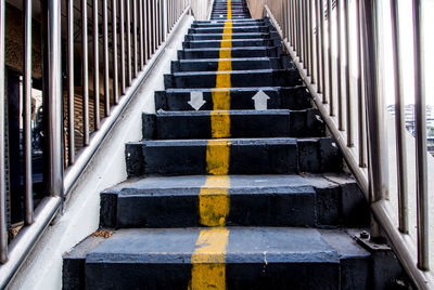 Yellow line and direction arrow painted on concrete stair of overpass