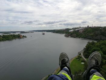 Low section of person by river against sky