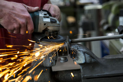 Cropped hand of worker cutting iron rod at industry