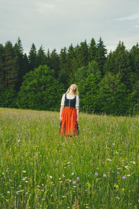 Rear view of woman standing on field against sky