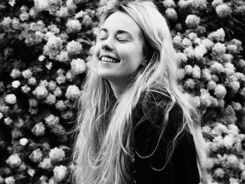 Close-up of smiling young woman against white flowering plants