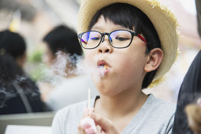 Boy emitting smoke while eating food
