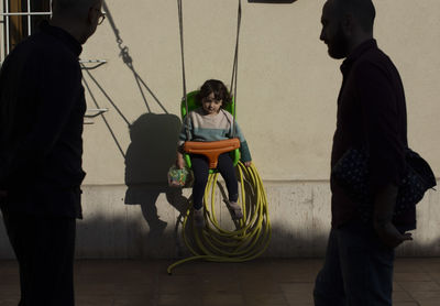 Kid on a swing against yellow wall