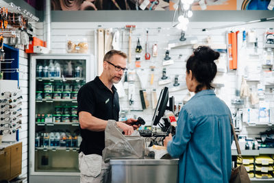 Female customer talking with shop owner at checkout counter in store