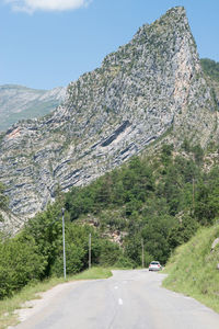 Road amidst trees and mountains against sky