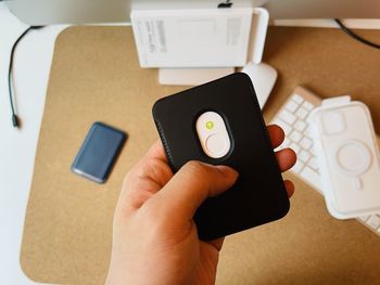 Midsection of person holding mobile phone on table
