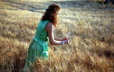 Side view of woman holding plant on field