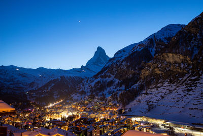 Illuminated buildings against clear blue sky during winter