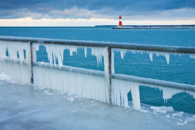 Icicles on railing with lighthouse in background