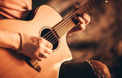 Midsection of man playing guitar