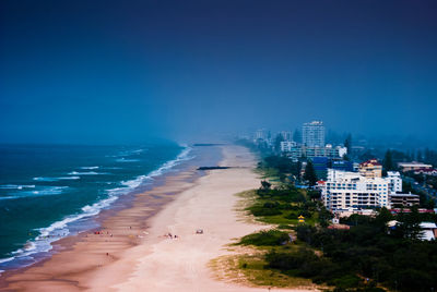 Scenic view of beach and buildings against clear blue sky