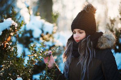 Young woman holding plant during winter