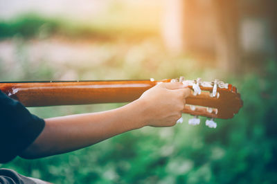 Cropped hand of person playing guitar over field