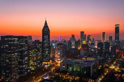 Illuminated buildings in city during sunset