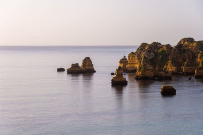 Scenic view of rock formation in sea against clear sky