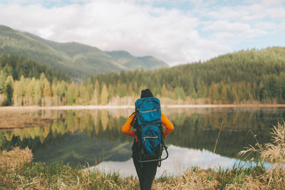 Rear view of woman standing by lake