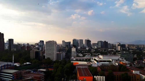 Aerial view of buildings in city against sky during sunset