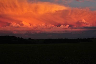 Scenic view of silhouette field against orange sky