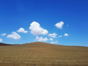 View of sand dunes in desert against blue sky