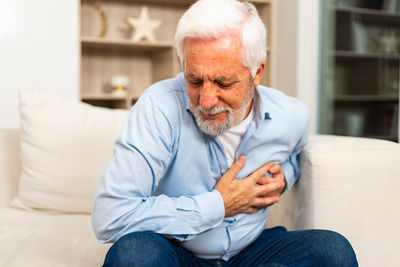 Senior man using mobile phone while sitting at home