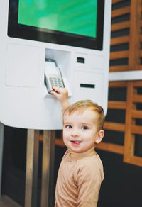 Smiling boy using machinery while standing at store