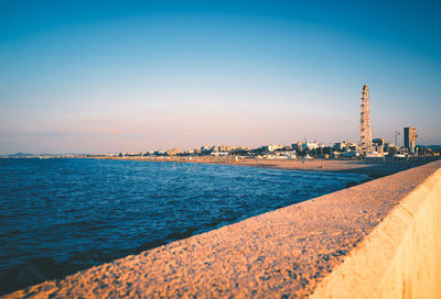 Scenic view of sea and buildings against clear blue sky