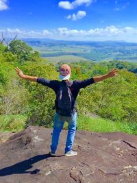 Full length of happy boy standing on landscape against sky