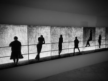 Rear view of silhouette people walking on railing