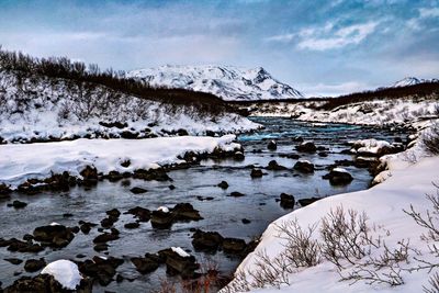 Scenic view of frozen river against snowcapped mountains during winter