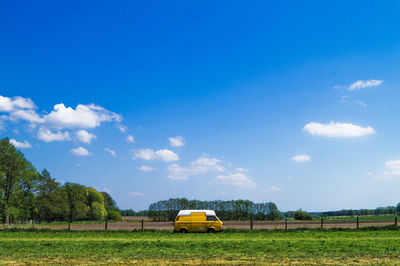Van parked by field against sky