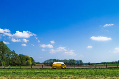 Yellow car on field against sky