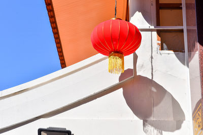 Red chinese lanterns on blue sky background, floating lanterns next to red steel post.