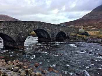 Arch bridge over river against sky