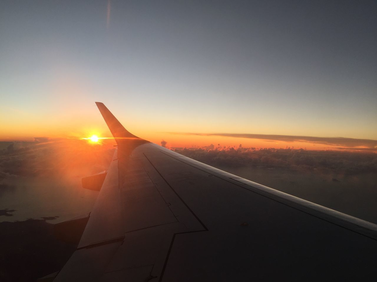 AIRPLANE FLYING OVER ORANGE SKY