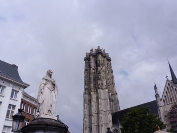 Low angle view of statue amidst buildings against sky