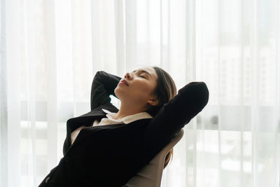 Low angle view of young man sitting on window