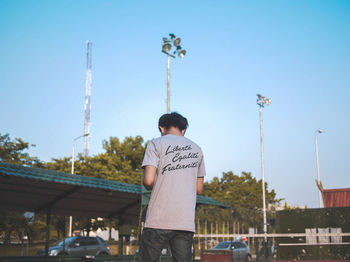 Rear view of man standing against clear blue sky