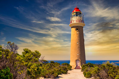 Lighthouse by sea against sky