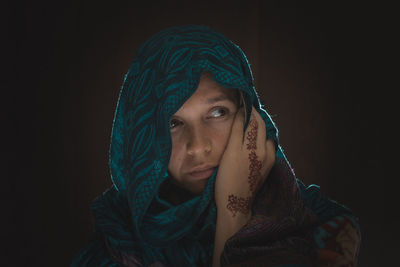 Portrait of young woman against black background