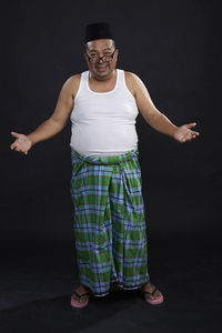 Portrait of smiling man standing against black background