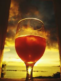 Close-up of beer glass against sunset