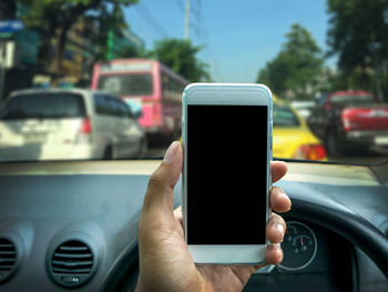 Close-up of human hand using mobile phone in car