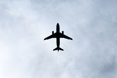 Low angle view of airplane flying against sky